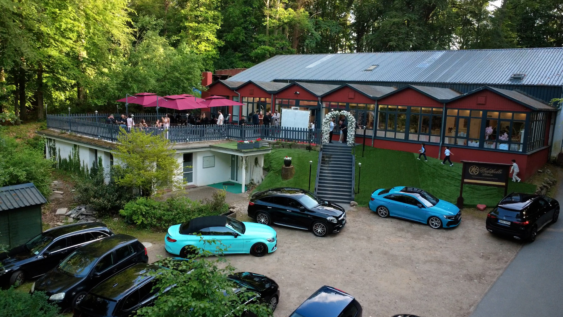 Atmosphärische Sicht auf die Waldhalle Büchen, Halle umgeben von hohen Bäumen, warmes Abendlicht
